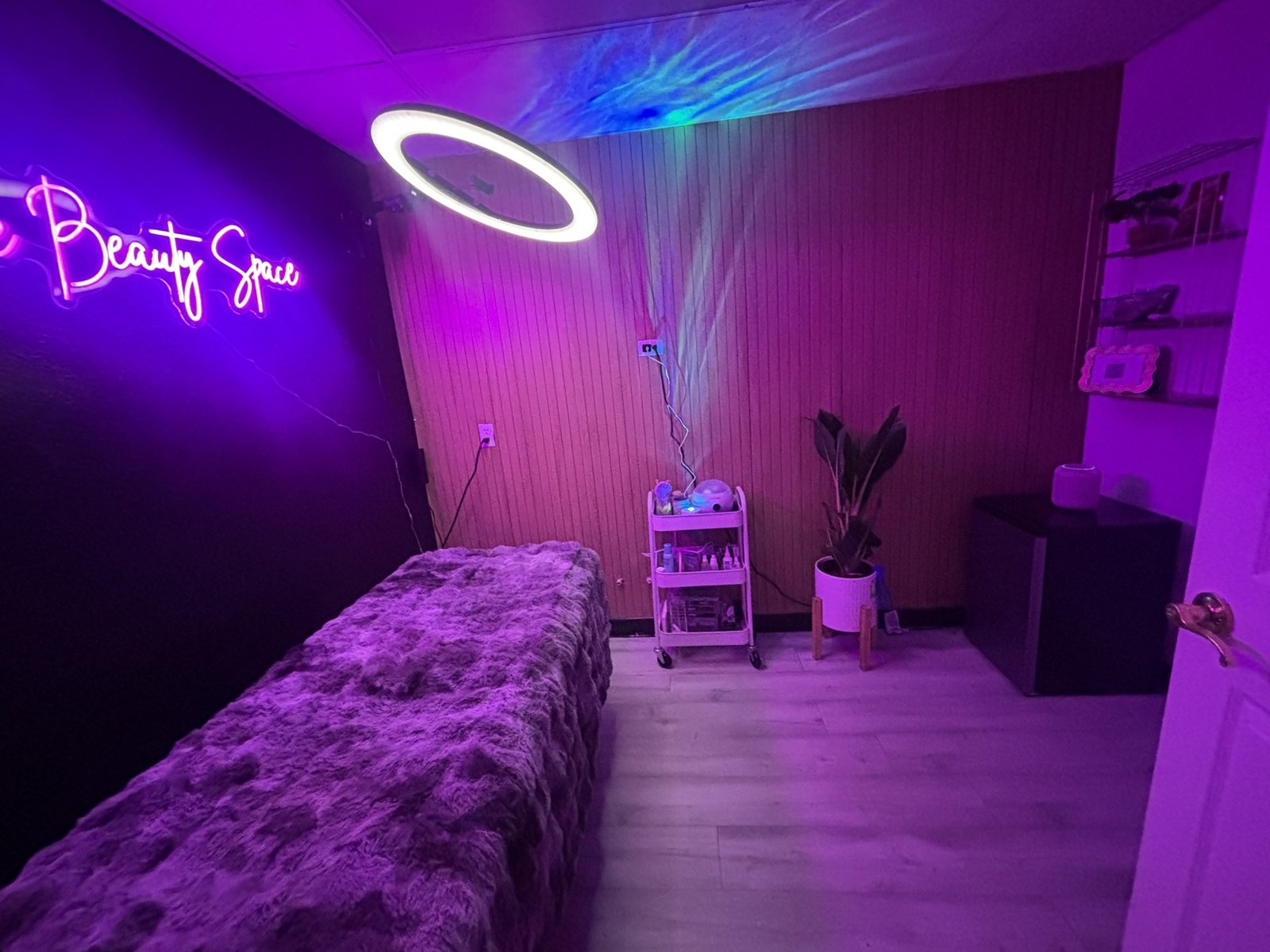 The Beauty Space private lash room with a neon sign, ring light and plush bed